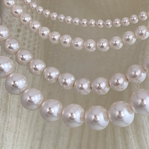 Detail of layered cream pearl necklaces with elegant luster on a beige knit fabric texture