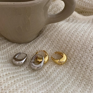 Eleganti orecchini a cerchio ovali spessi in oro e argento su morbido tessuto a maglia