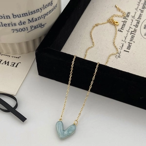 Dettaglio di un ciondolo a cuore in marmo azzurro su una sottile catena dorata