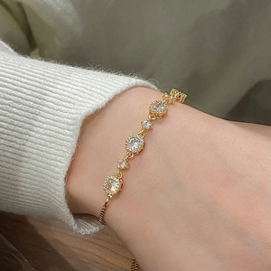 Elegant gold adjustable bracelet with sparkling round cubic zirconia stones on a knit sleeve