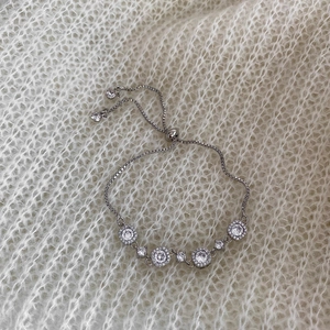 Detail of silver adjustable bracelet with sparkling zircon clusters on knit background
