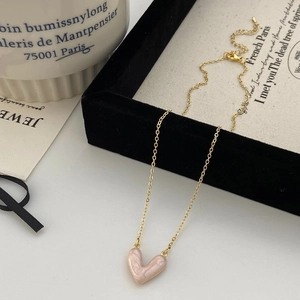 Dettaglio di una collana a cuore dorata con texture in marmo rosa su vassoio di velluto