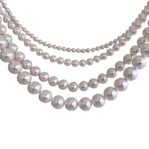 Elegant layered white pearl necklace with four strands of varying sizes on white background