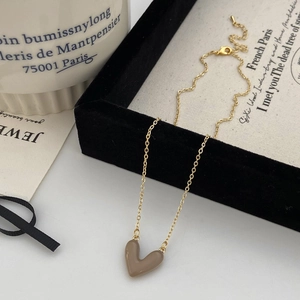 Dettaglio della collana con ciondolo a cuore cachi e catena dorata su velluto