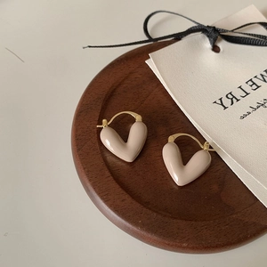 Détail de boucles d'oreilles cœur nude avec fermoir doré sur un plateau en bois
