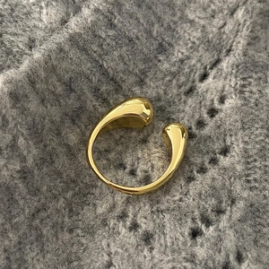 Macro detail of gold teardrop open ring on textured grey knit background