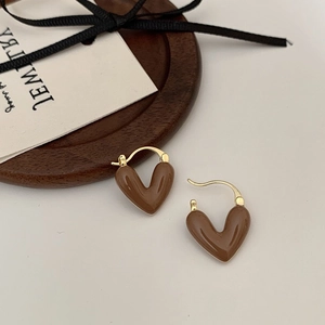Gros plan de boucles d'oreilles cœur marron avec détails dorés sur plateau bois