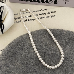 Détail d'un collier de perles élégant avec fermoir mousqueton argenté sur tissu