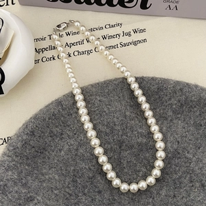 Détail macro d'un collier de perles blanches avec fermoir sur tissu en tweed