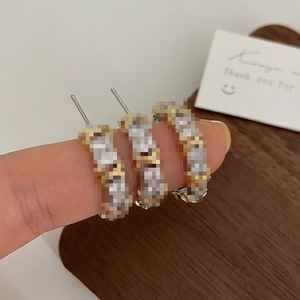 Macro detail of criss-cross textured hoop earrings in gold and silver finish