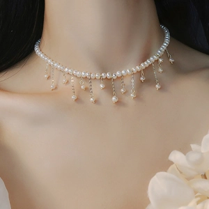 Détail d'un collier de perles baroques avec franges dorées porté par un mannequin