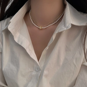 Gros plan d'un collier double épaisseur doré avec perles et sphère diamantée sur mannequin