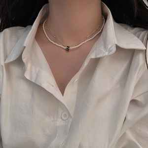 Gros plan d'un collier double rang doré avec perles et pendentif pavé de pierres noires