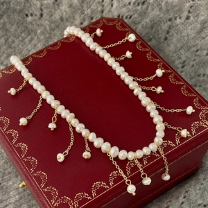 Détail du collier de perles d'eau douce baroques avec pompons dorés élégants