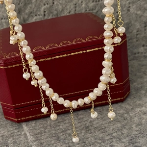 Collier de perles d'eau douce baroques avec pendentif à franges dorées sur une boîte rouge