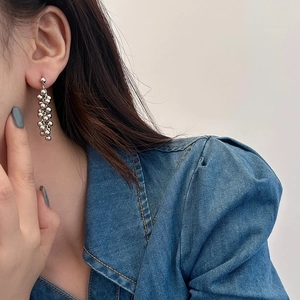 Detail of silver metallic beaded tassel earrings featuring a cluster of polished spheres