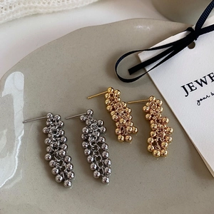 Macro detail of gold and silver beaded tassel earrings on a ceramic jewelry tray