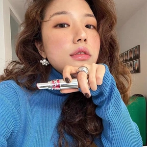 Dettaglio di orecchini a perla floreali abbinati a un dolcevita in maglia blu elegante