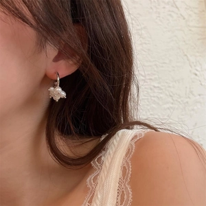 Dettaglio di eleganti orecchini a perla a forma di fiore indossati da una modella
