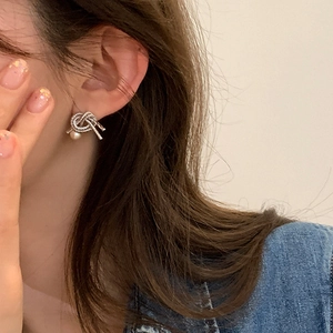 Detail of silver knot stud earring with pearl on a female model with vintage style