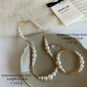 Detail of elegant pearl necklace and bracelet set with gold metallic tube accents