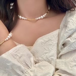 Detailed view of elegant pearl necklace and bracelet set on a model with gold accents
