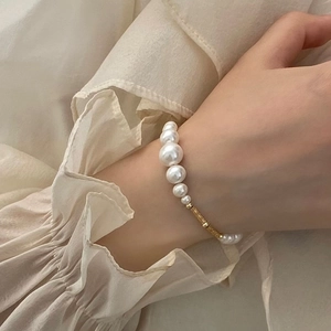 Detail of elegant pearl bracelet with gold textured tube bead on a model wrist