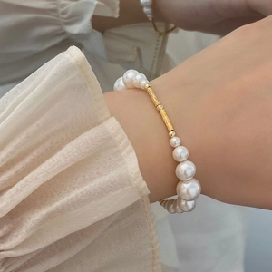 Elegant pearl bracelet with gold metal tube and gradient pearls on woman wrist