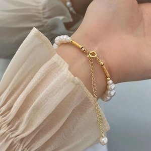 Detail of pearl bracelet with gold textured tubes and adjustable chain on a wrist