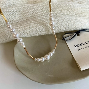 Macro detail of gradient pearl necklace with engraved gold tubes on a ceramic plate