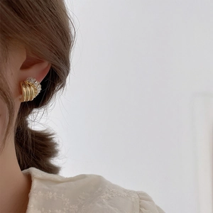 Elegant gold C-shaped earrings with layered metal bars and zircon stones on model