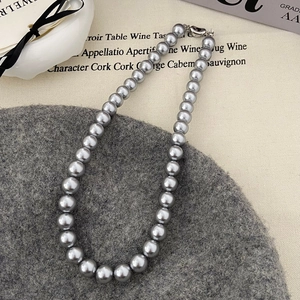 Détail macro d'un collier de perles gris argenté avec éclat métallique et fermoir argent