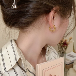 Détail de créoles texturées en or 18 carats avec design torsadé portées par un mannequin