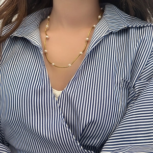 Detailed view of an 18K gold-tone twisted chain necklace with freshwater pearls on a model