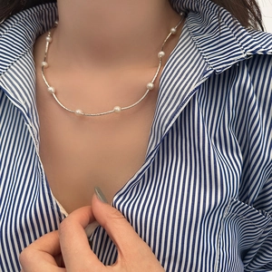 Close-up of minimalist freshwater pearl necklace on a silver chain worn by a model