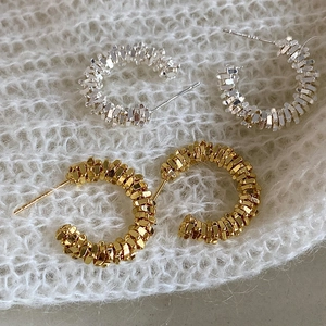 Boucles d'oreilles créoles C texturées dorées et argentées sur tricot blanc doux
