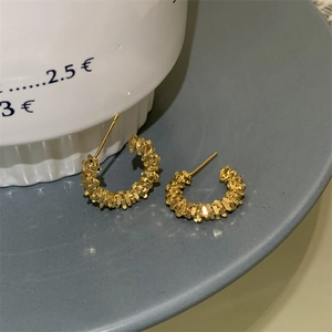 Détails de boucles d'oreilles dorées en forme de C avec un design en argent concassé