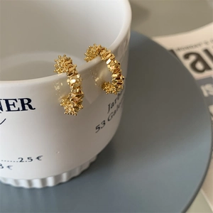 Vue macro détaillée des boucles d'oreilles dorées en forme de C avec texture pailletée