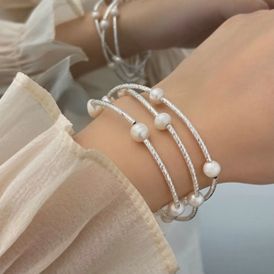 Detail of multi-layer textured silver bracelet with freshwater pearls on a model