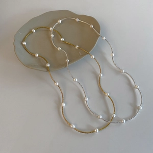 Close-up of minimalist gold and silver pearl necklaces on a modern ceramic plate