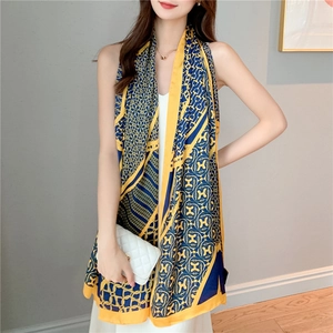 Detail of elegant navy and yellow silk scarf with H-letter chain patterns and gold border
