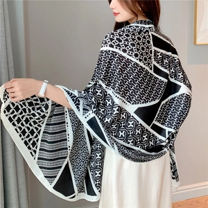 Elegant black and white silk shawl featuring H-letter and chain print on a female model