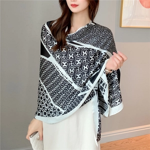 Close-up of elegant black and white silk scarf featuring horse chain and H patterns