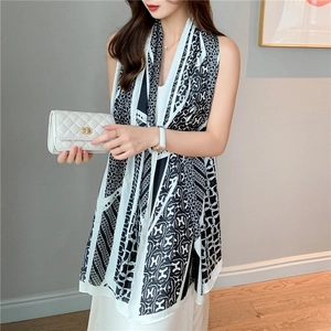 Detail of elegant black and white silk scarf with geometric H pattern draped on a model