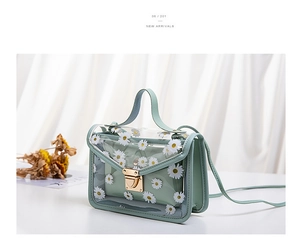 Detail of mint green transparent PVC jelly bag with white daisy patterns and gold clasp
