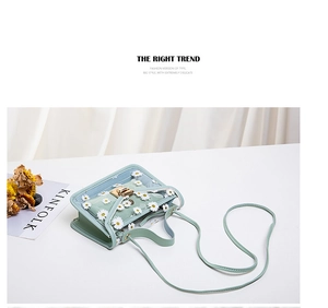 Detail of light green jelly bag featuring white daisy embroidery and gold twist lock