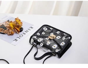 Detail of transparent PVC daisy crossbody bag with black leather trim and gold buckle