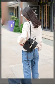 Outdoor shot of a black mini leather backpack with contrast strap and gold buckle