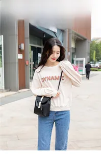 Outdoor street style view of a black leather bucket crossbody bag with drawstrings