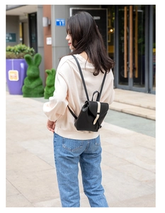 Detail of a mini black backpack with a contrasting white vertical strap and metal buckle